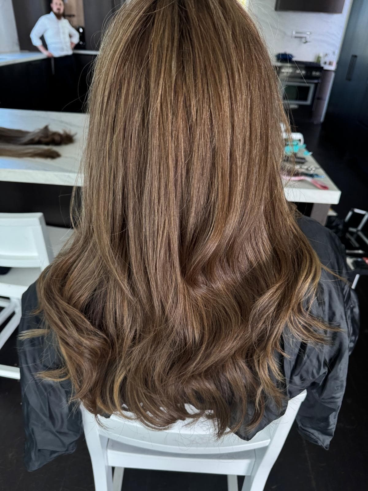 Back view of long, light brown hair with subtle highlights and soft, wavy ends.