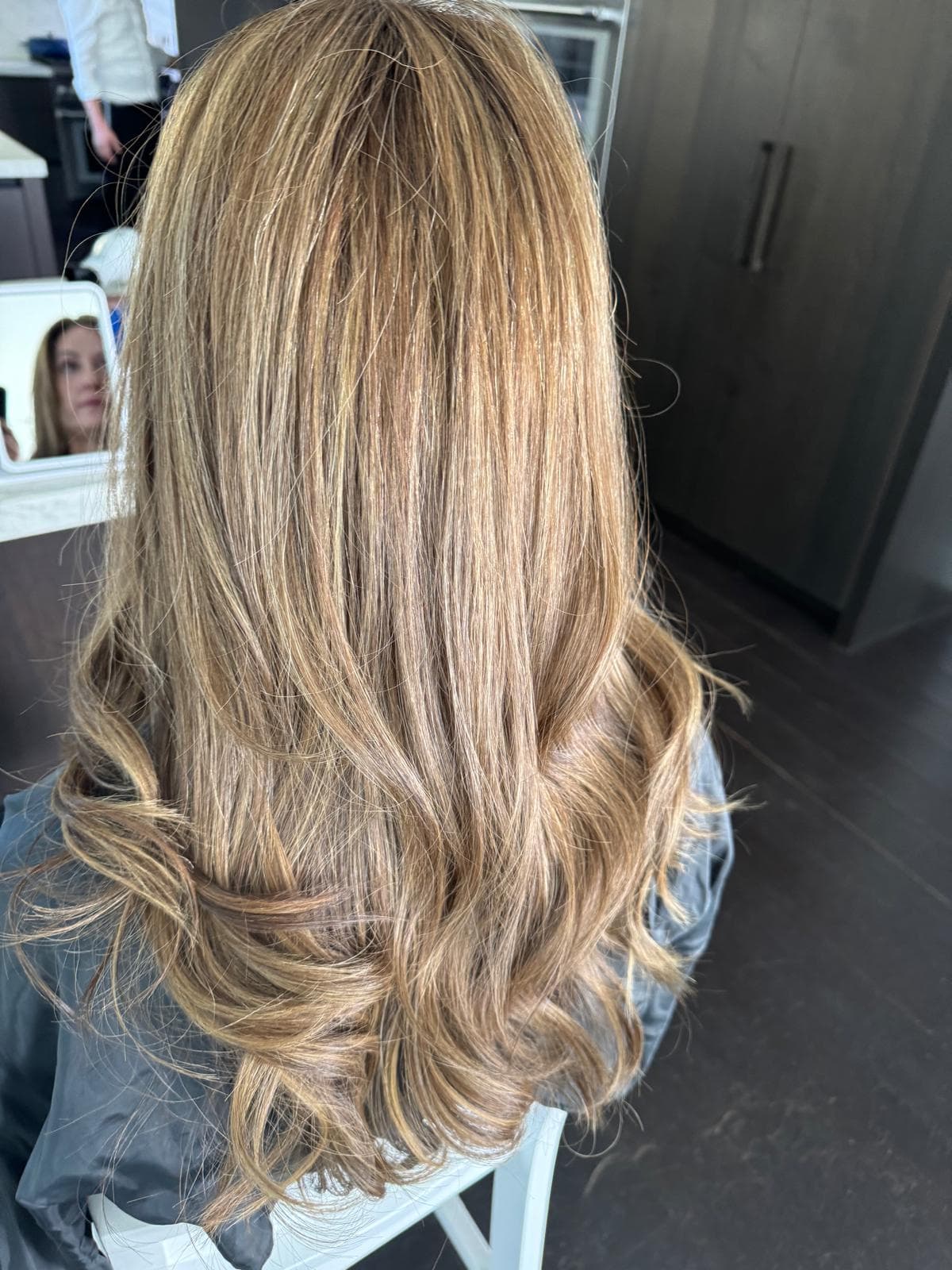 Long, layered honey-blonde hair with golden highlights and soft, loose waves at the ends.