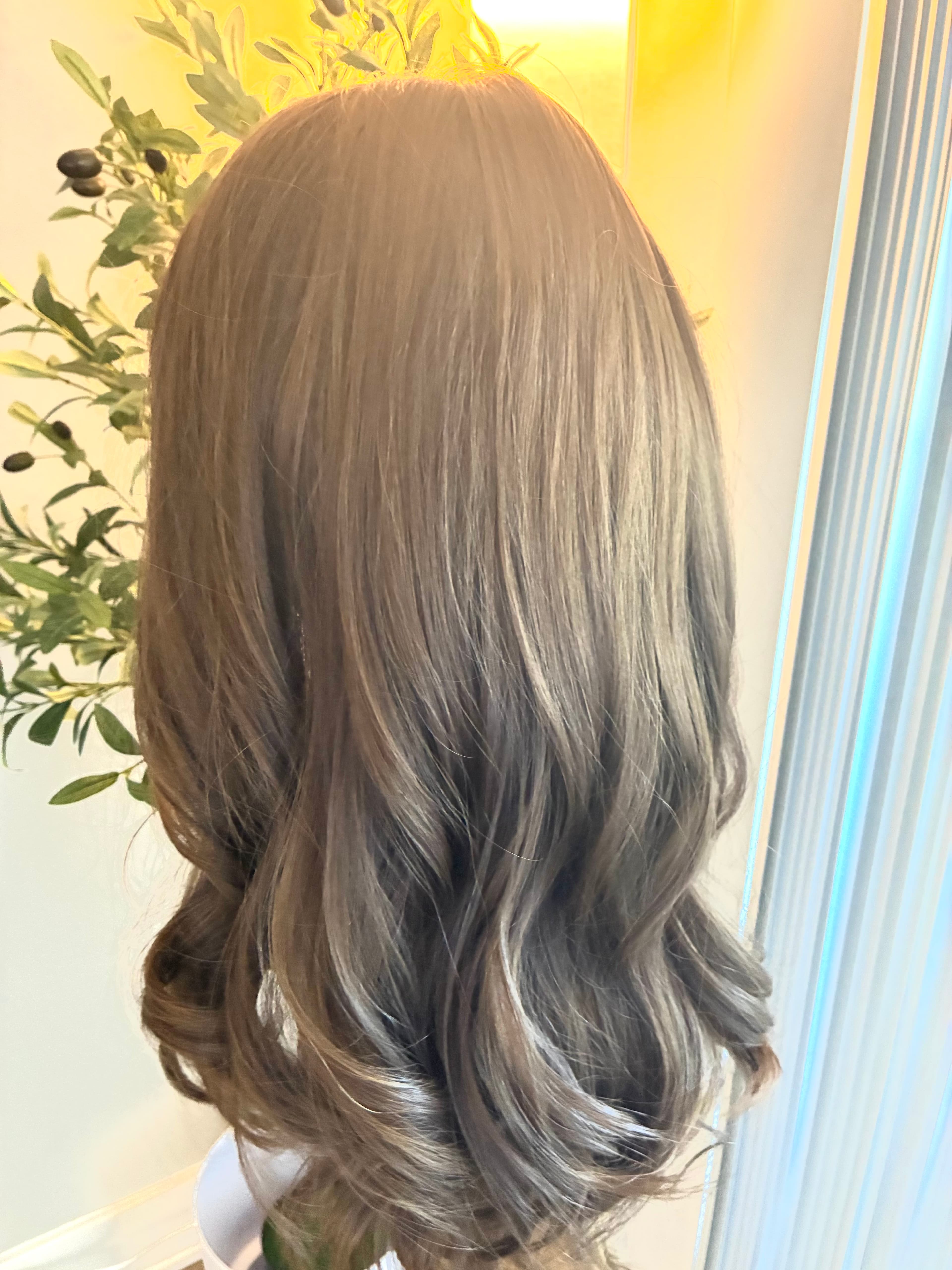 Long, wavy ash brown hair with soft curls and subtle highlights, viewed from behind.
