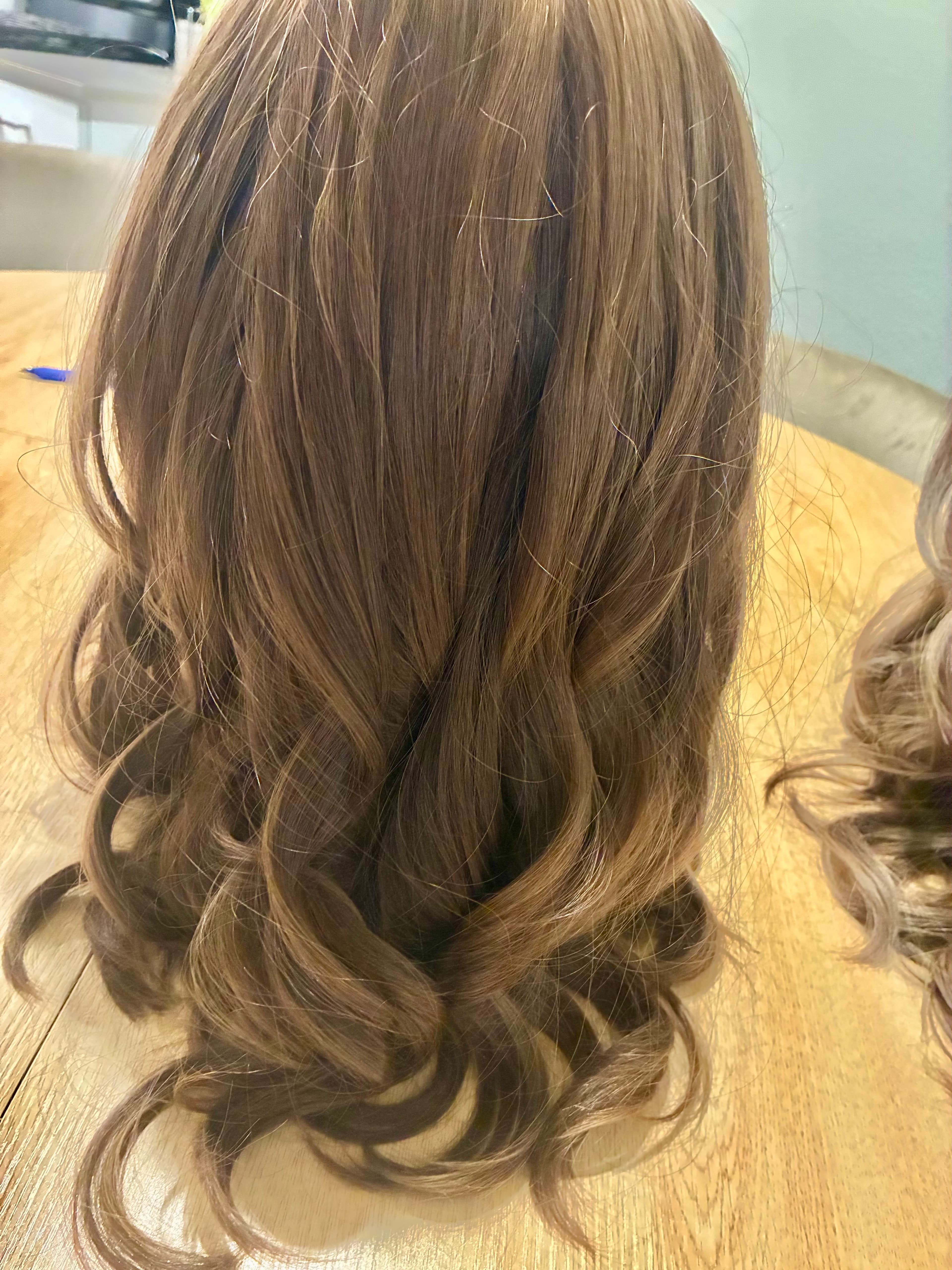 Long light brown hair with straight roots and large, loose curls at the ends.