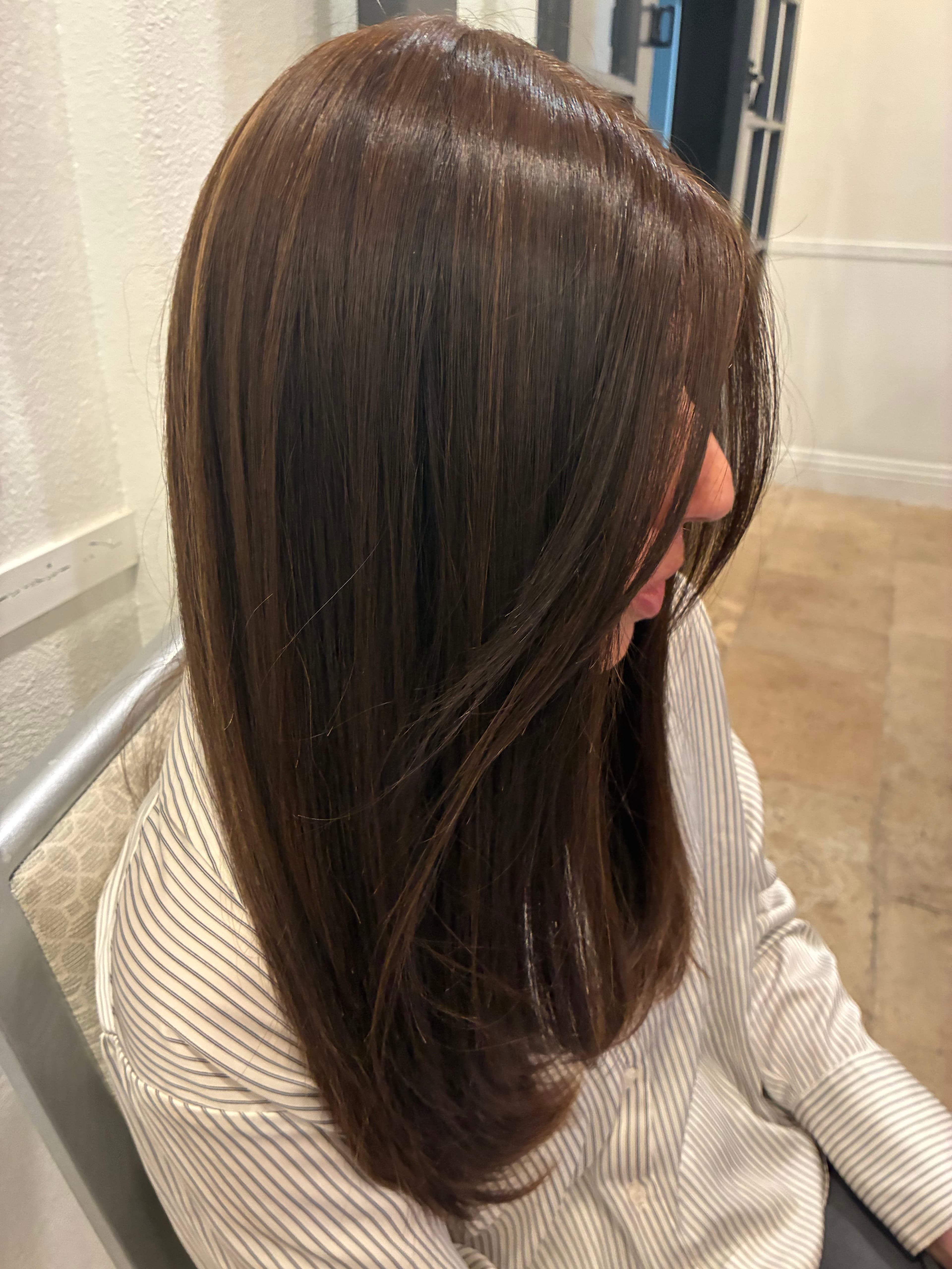 Long, straight dark brown hair with subtle highlights, seen from a side profile view.