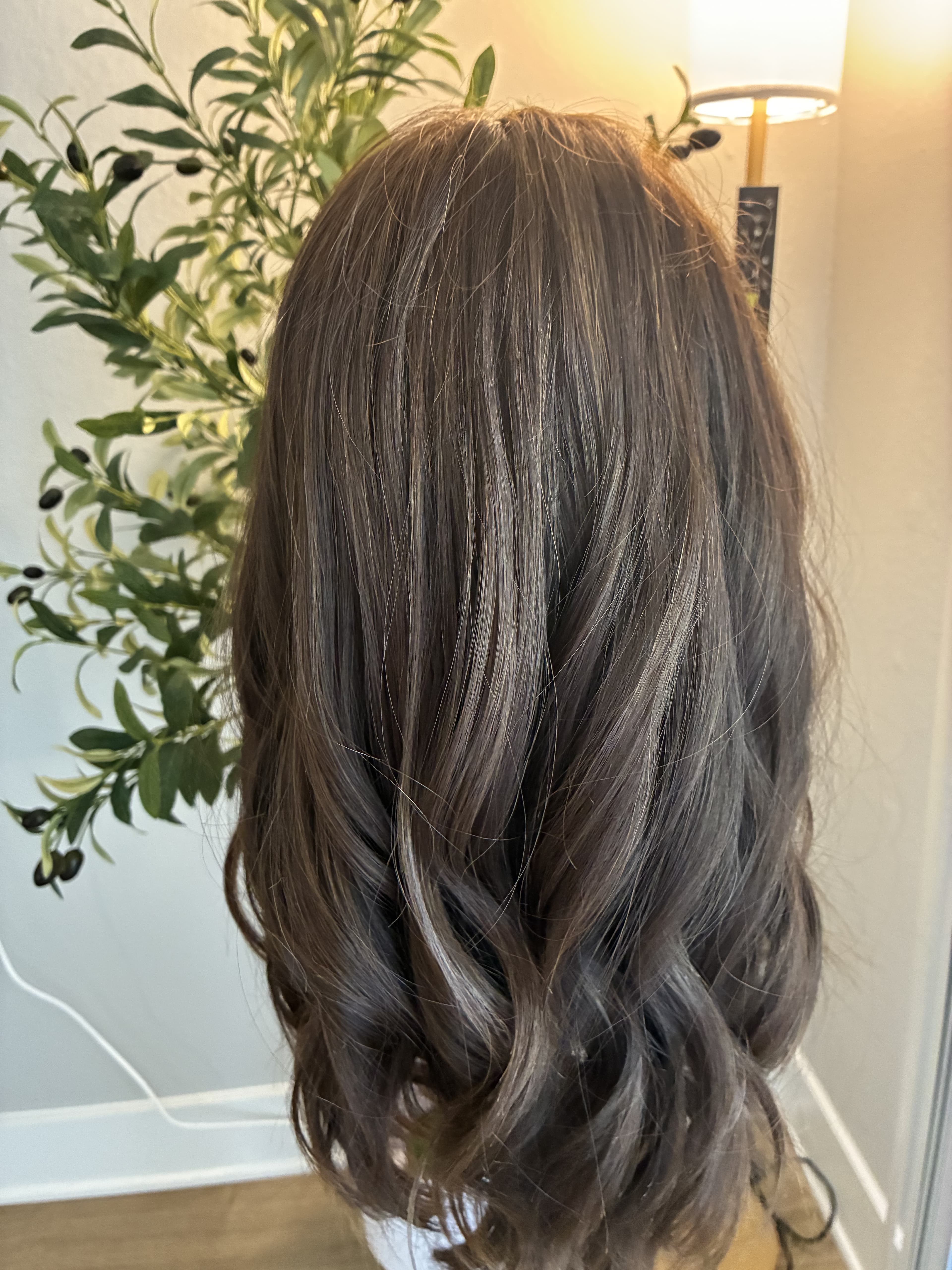 Long, wavy dark brown hair with subtle highlights and soft curls at the ends.