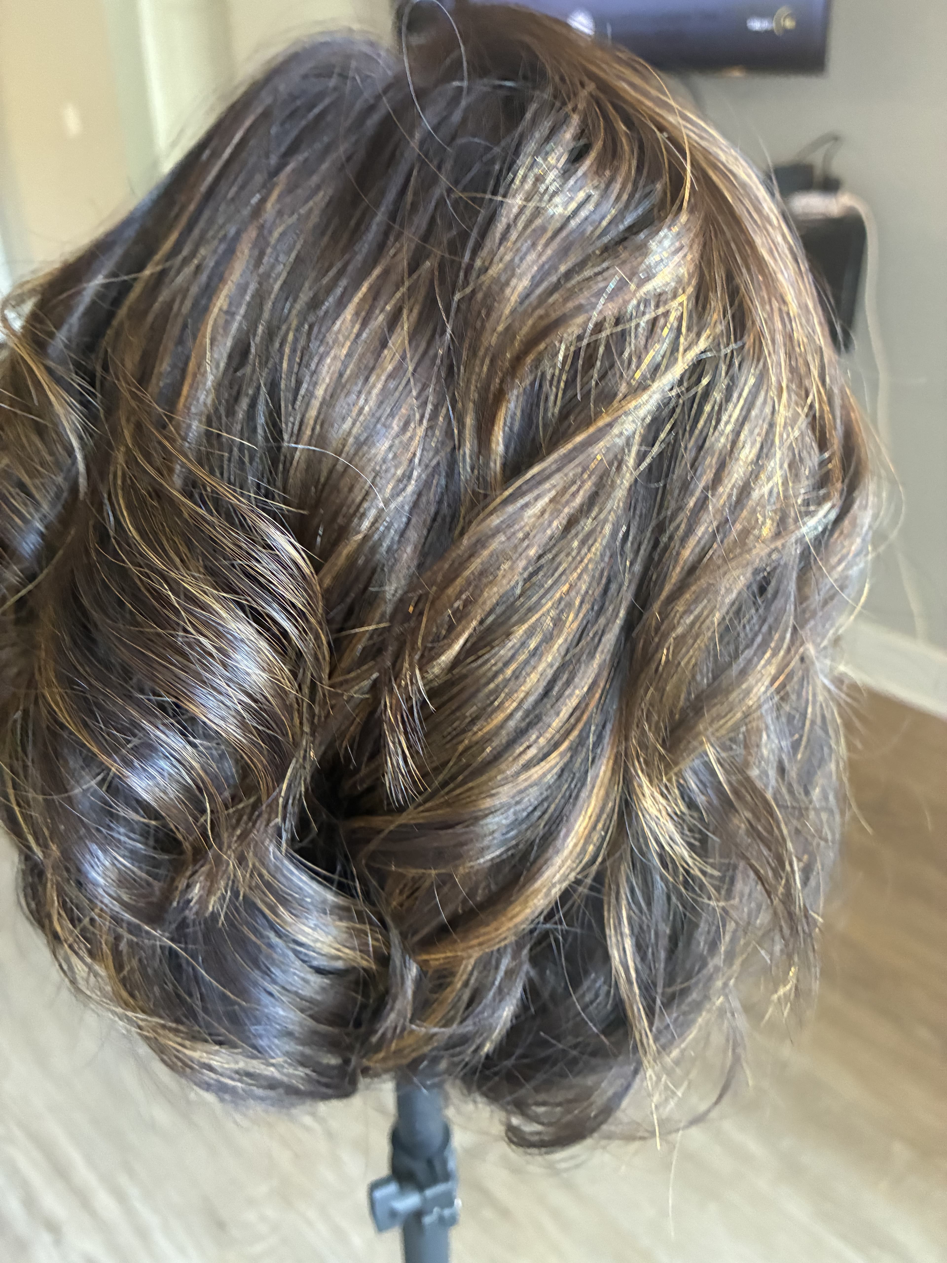 Dark brown hair with golden-blonde highlights styled in loose, textured waves on a mannequin.