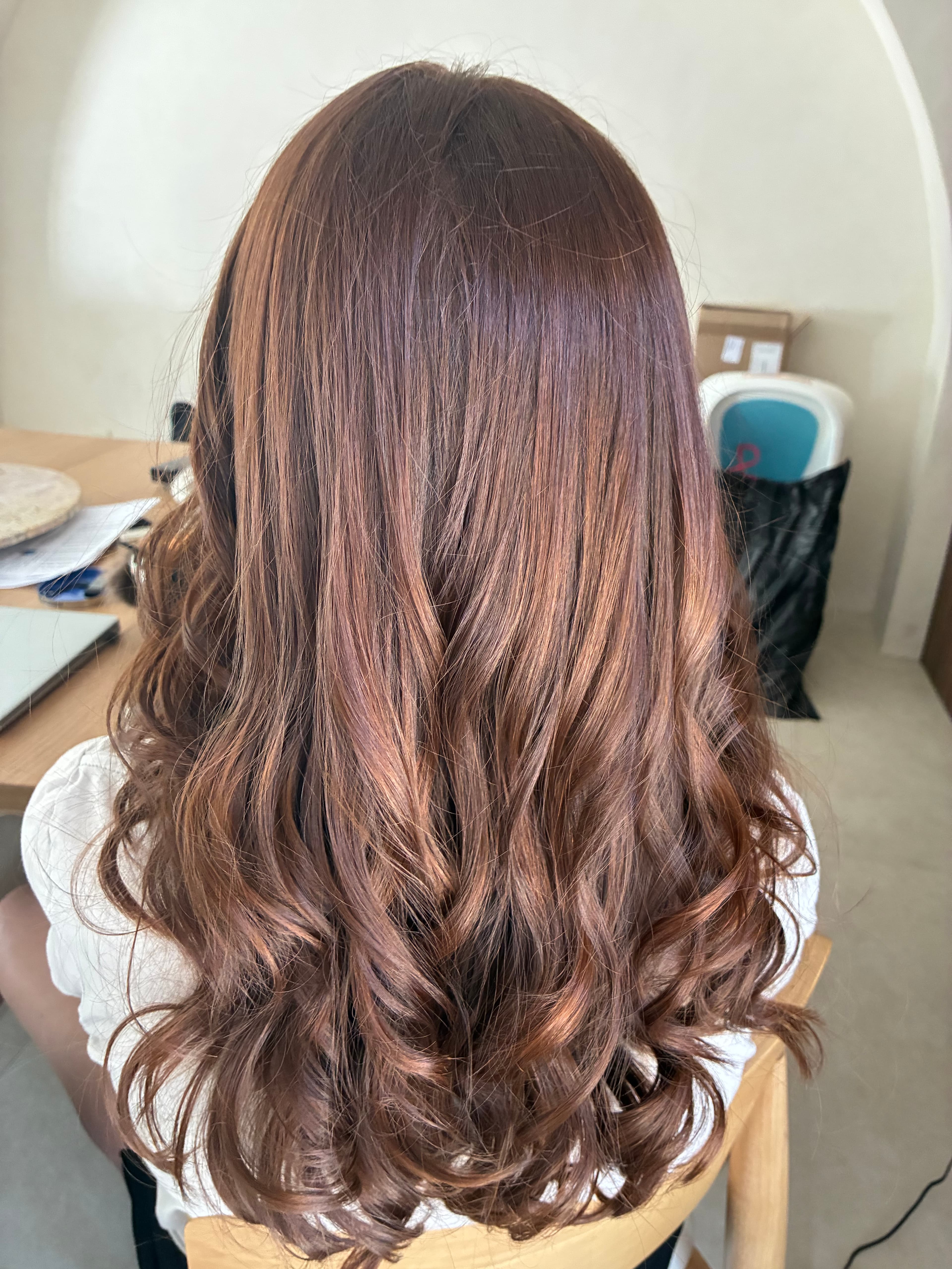 Long, wavy brown hair with auburn highlights, cascading in loose curls down the back.