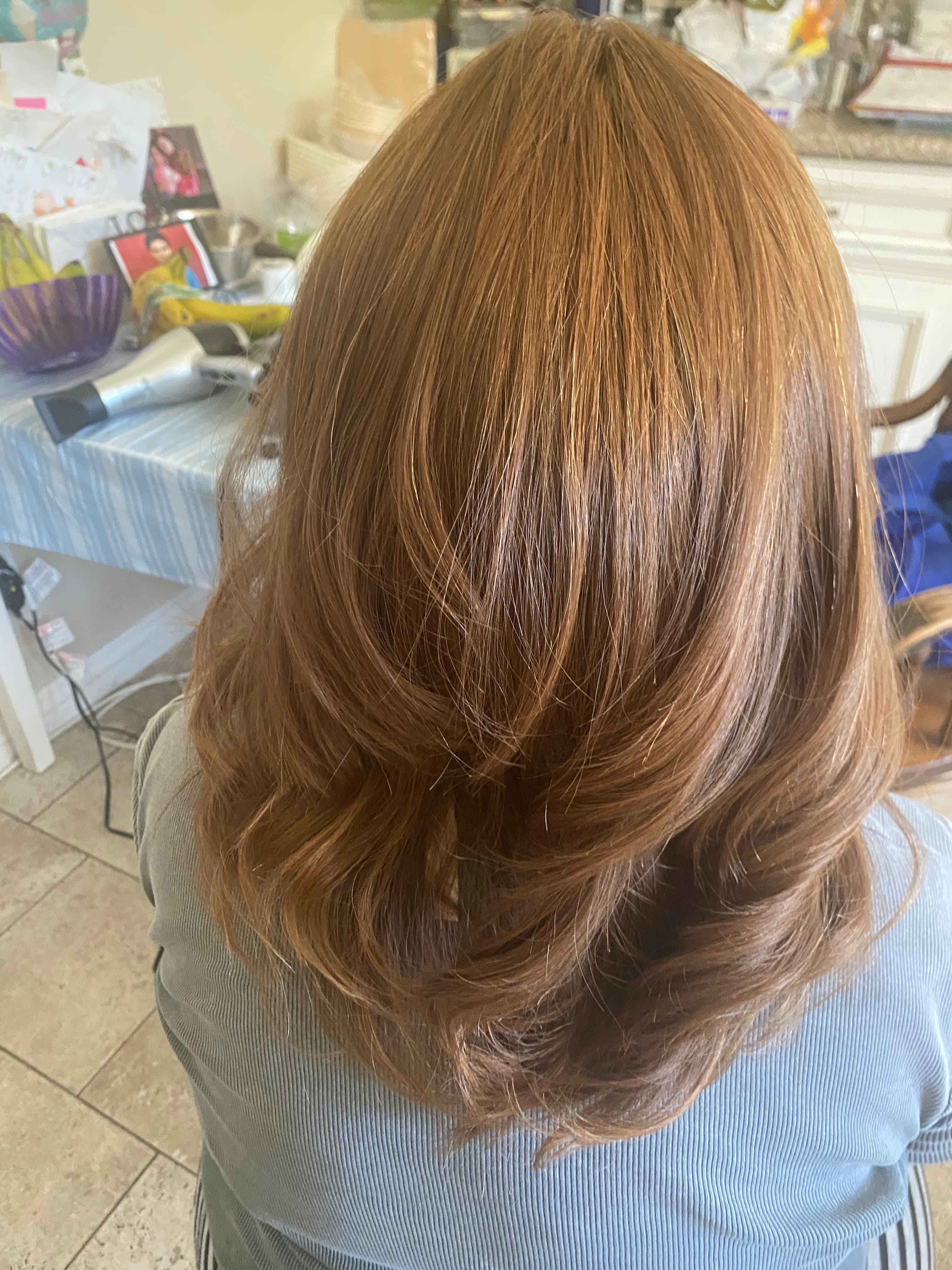 Back view of shiny, layered auburn hair styled with voluminous waves at the ends.